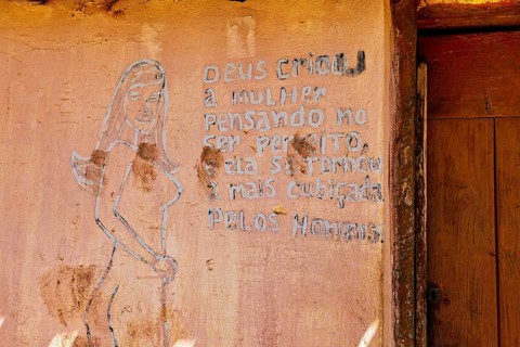 Faded wall drawing with writing and a sketched woman on an old wall next to a wooden door, painted