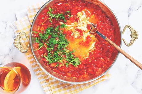 Traditional Turkish dish, scrambled eggs with tomatoes, Menemen, with herbs, in a frying pan,