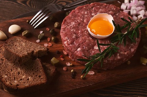 Beef tartare, with egg, capers, gherkins and bread, toned, top view, close up, horizontal, no