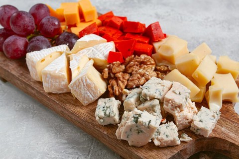 Assorted cheese on a wooden board, with grapes and walnuts, appetizer, no people