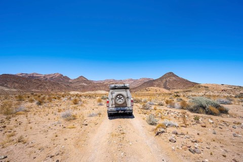 Toyota Hilux off-road vehicle on a sandy track, desert landscape with Brandberg, Erongo,