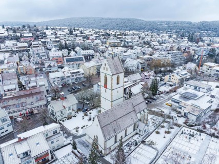 Snow-covered village centre with a large church and surrounding houses in a wintry landscape,