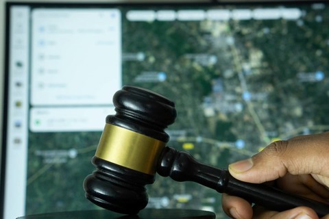 Dhaka, Bangladesh- 20 June 2025: A hand holds a gavel in front of a computer screen displaying