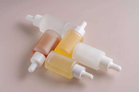 A top view of assorted dropper bottles with varying translucent hues, neatly arranged on a smooth
