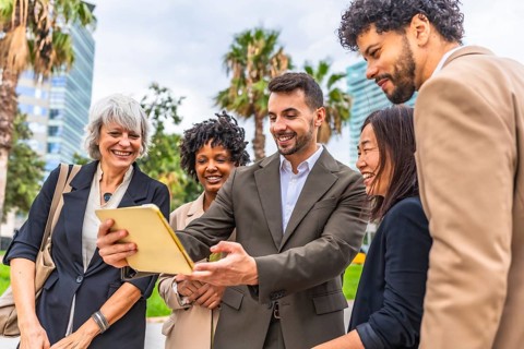 Multi-ethnic group of people using digital tablet during outdoor meeting in the financial district