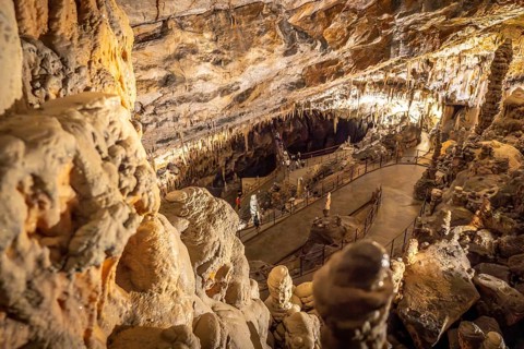 Tourists are enjoying a visit to the famous postojna cave in slovenia, walking on the footpath