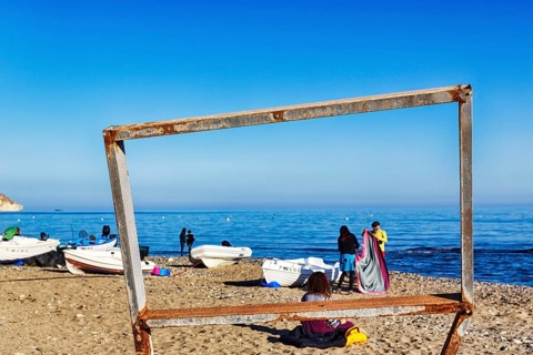 View through wooden scaffolding of walkers and fishing boats, picture frame, Playa de las Negras,