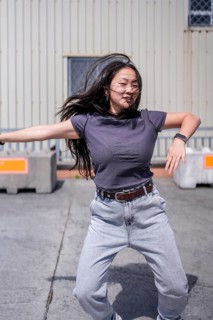Vertical photo of a beauty female asian dancer moving arms in a futuristic robotic way dancing