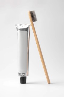 Eco-friendly bamboo toothbrush alongside a sleek toothpaste tube, set against a minimalist white