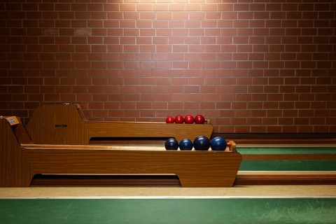 Interior view of a classic bowling alley with wooden track, green playing area and red and blue
