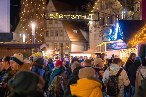 Large crowd at a brightly lit Christmas market with historical flair, Christmas market, Nagold,