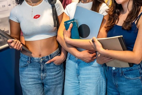 Female university students walk across campus carrying laptops, books and reusable water bottles,