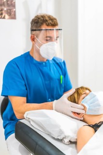 Cranial massage on the head of a physiotherapist with protective measures to a young blonde patient
