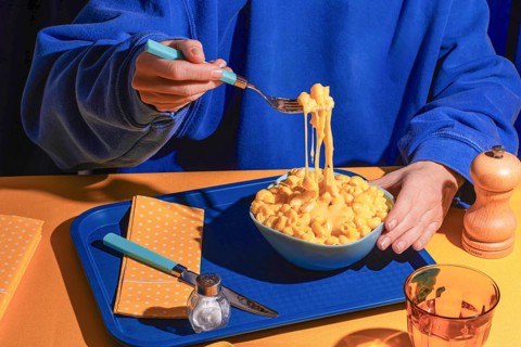 A cozy scene featuring a person enjoying a bowl of creamy macaroni and cheese. The rich, melted