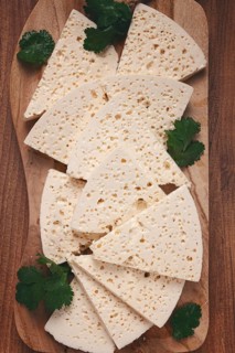 Sliced Georgian cheese, factory grade, on a wooden board, top view