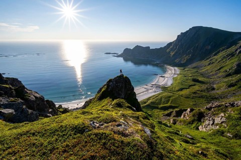 Climber on a rock, view of picturesque coastal landscape with sun star, steep coast with peak
