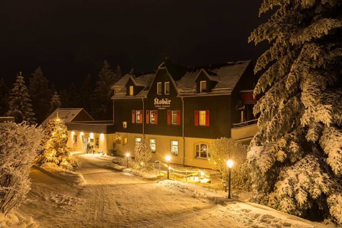Snow-covered Gasthaus Kobär with Christmas tree at night, winter in Oberbärenburg, Altenberg,