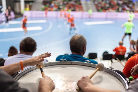 Supporters drum during handball match.