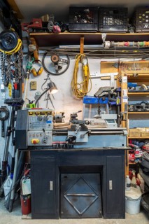 Craftex metal lathe machine with various objects, items and parts hanging on wall and on wooden
