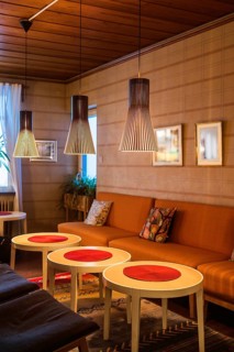 A cozy lounge in Stockholm with modern pendant lamps, orange sofa, and stylish round tables. Warm