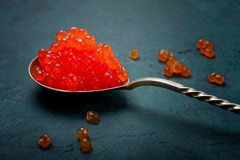 Spoons with red caviar, imitation, on a dark background, no people