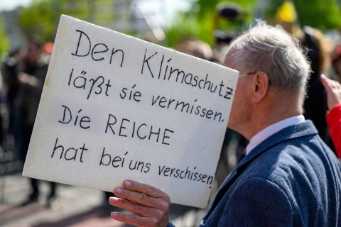 Man with sign They miss climate protection. The rich have shot us at the Fridays for Future