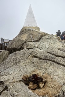 Stone pyramid on rocks in the fog on a raised platform, The summit of Fansipan near Sa Pa in