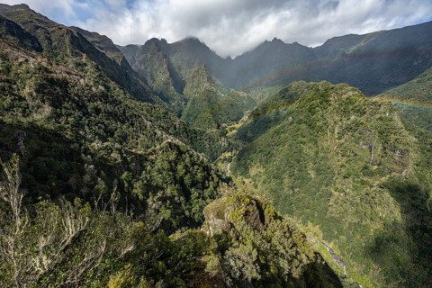 Densely overgrown steep mountains with rainbow, green mountain landscape, view from Miradouro dos