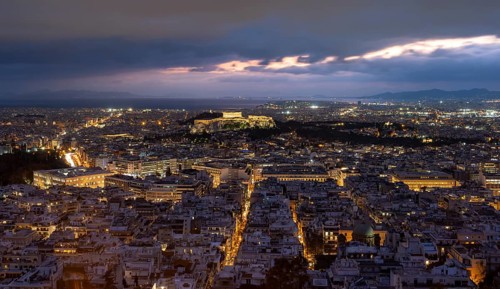 View over the sea of houses of Athens, illuminated Parthenon temple on the Acropolis, dramatic