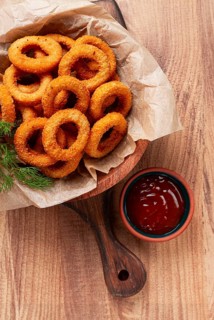 Deep fried onion rings, appetizer, with tomato sauce, on a wooden table, no people, favorite dish