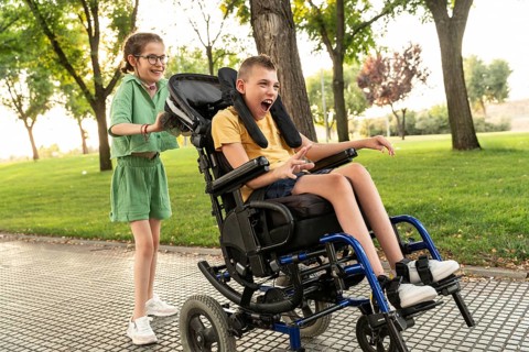 Two children with disabilities enjoy a sunny day in the park. The boy in a wheelchair has cerebral