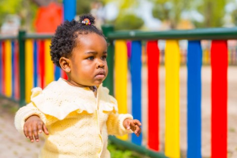Side view close-up portrait of a cute african baby girl in a colorful playground