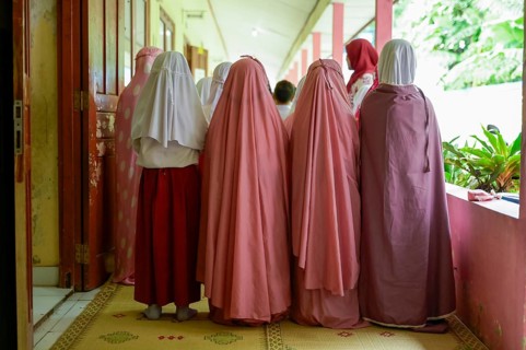 Back view of unrecognizable women, dressed in soft pink and maroon traditional burqa and hijab