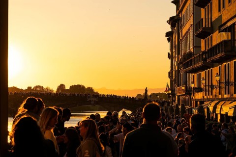 Crowd at sunset on the river Arno, light-filled evening mood, back light, old town, Florence,