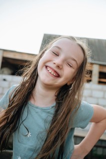A happy girl with a big smile plays and enjoys herself at an unfinished construction site,