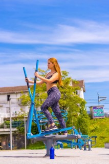 Red-haired woman with purple leggings and black overalls exercising on the machines, sport in the