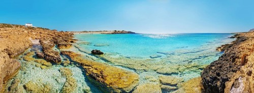 Rocky coast at Diakoftis sandy beach with crystal clear water, surrounded by quiet, unspoilt
