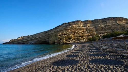 Neolithic caves, former hippie paradise, sandy beach with umbrellas and impressive rocks in front