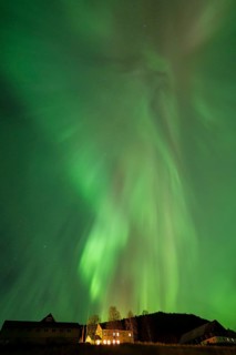Intense northern lights (aurora borealis) over an illuminated house, Alvdal, Hedmark, Innlandet,