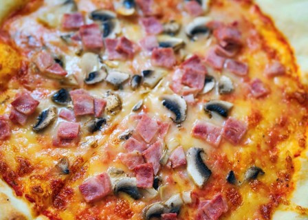 A delicious pizza topped with savory ham, mushrooms, and gooey cheese on a golden crust. Perfectly