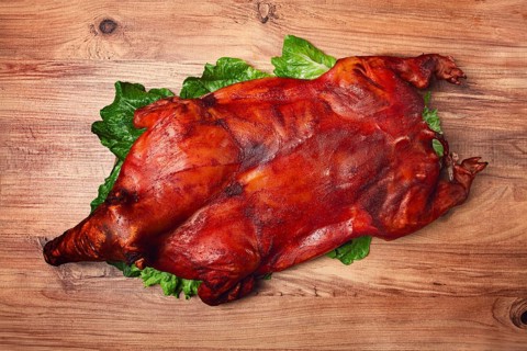 Baked, fried piglet, on a wooden table, no people, The whole piglet is baked and served on the