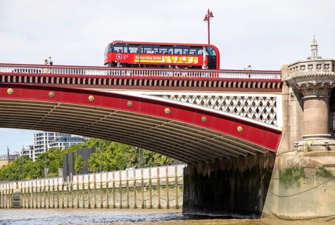 Red double-decker bus crossing Blackfriars Bridge, view from River Thames, London, England, UK