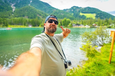 Tourist enjoying summer holidays at lake dobbiaco in the italian dolomites, taking a selfie and
