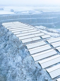 Solar panels on a snow-covered hill in a wintry landscape and fog, Nagold, Black Forest, Germany