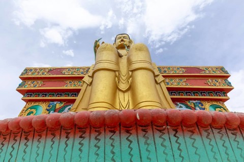 Stunning low angle view of a golden Buddha statue against a vibrant sky, located in the serene