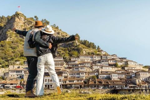 Happy travel couple embracing enjoy arms up vacation visit Mangalem Berat Old Town UNESCO Albania