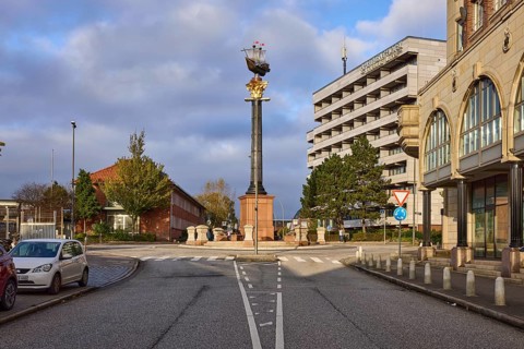 Granite column with metal sculpture of Störtebeker's cog, blue sky with cumulus clouds and