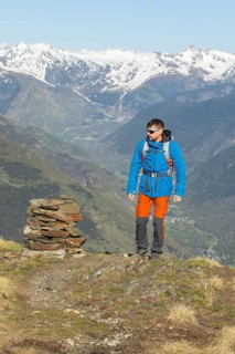 A man enjoys a trekking adventure in the stunning Pyrenees mountains, clad in vibrant outdoor gear.