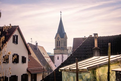 Church tower towers over the roofs of a peaceful village in mild spring weather, Gechingen, Calw