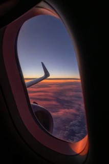 A captivating view from an airplane window showing a vibrant sunset with pink and purple clouds.